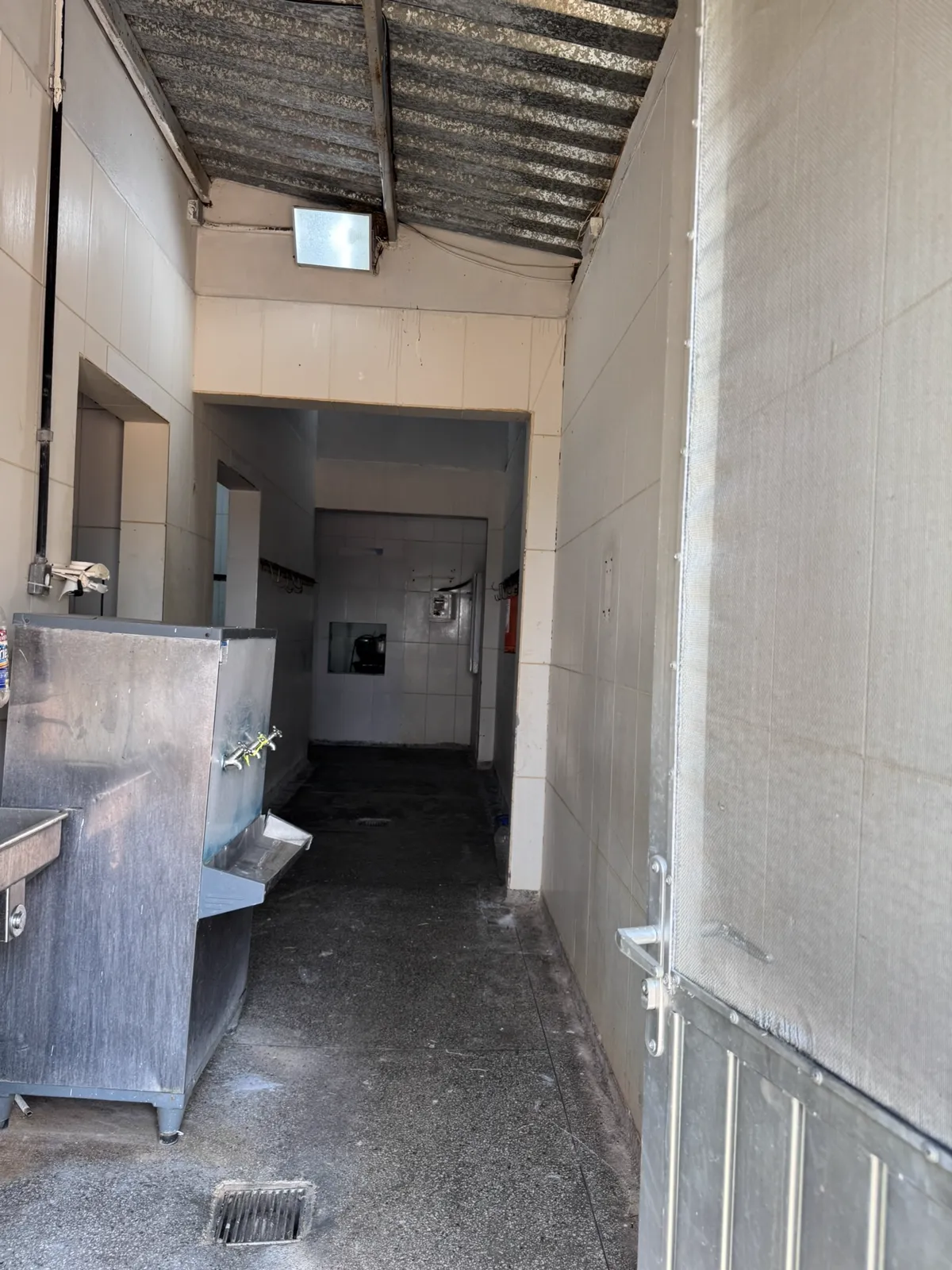 Corredor de higienização com pia de inox e ralo no piso.